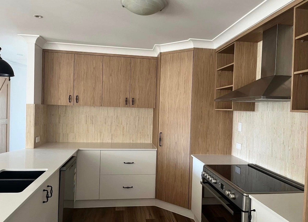 Light-wood kitchen with reeded splashback and stone bench