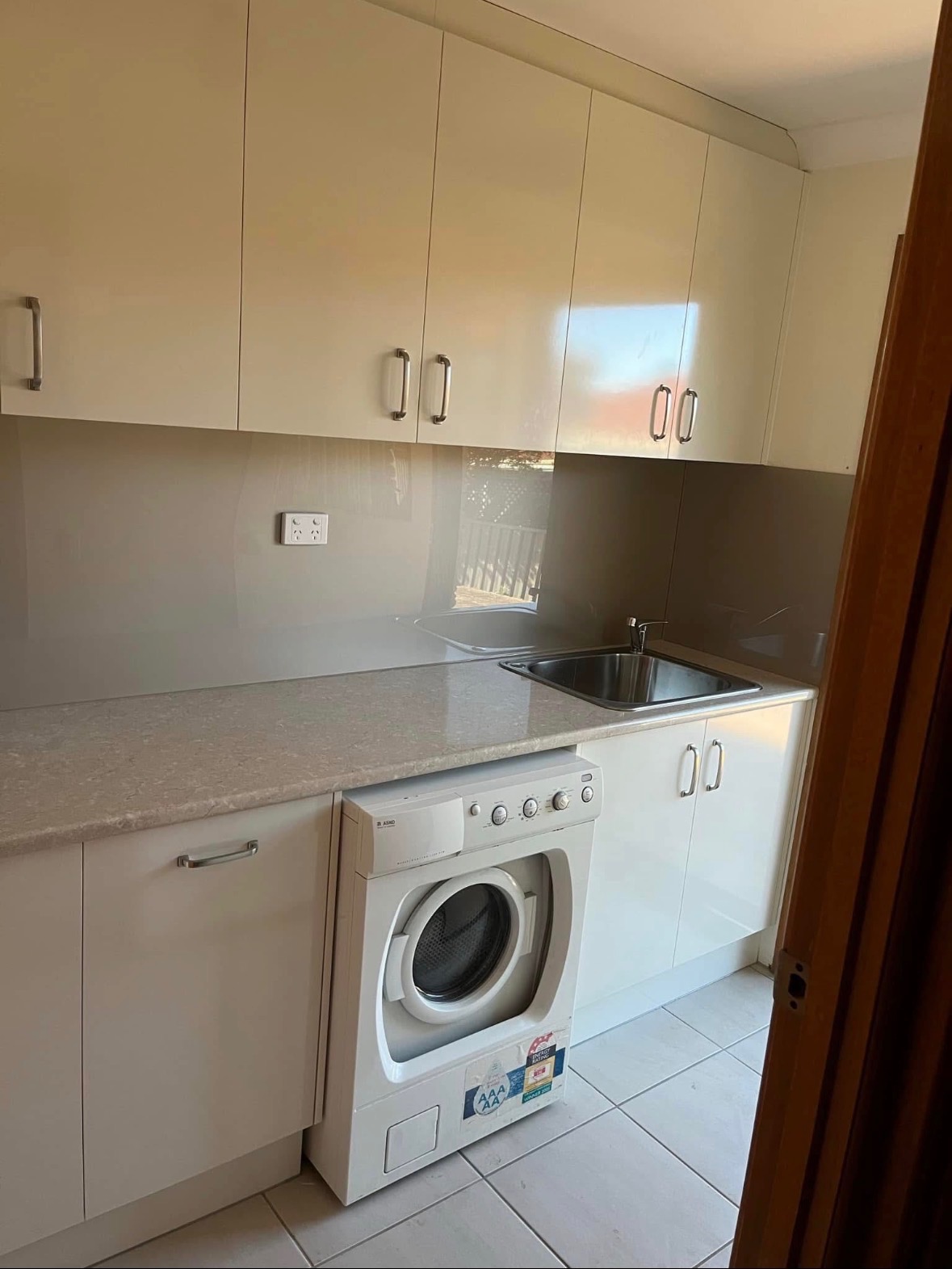 Cream-finish laundry with overhead cabinetry and integrated washer