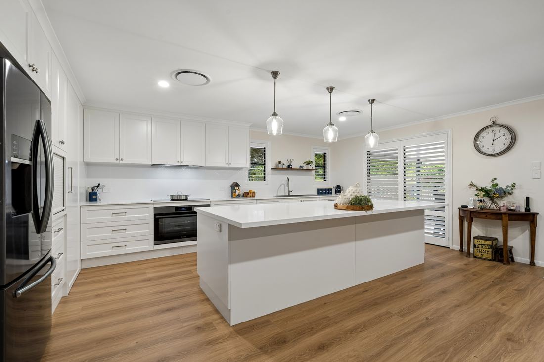Wide view of the white Shaker kitchen with waterfall island and oak flooring — Placid Hills