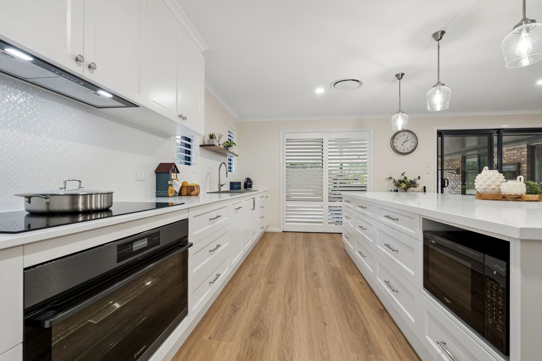 Galley view through the kitchen with pendant lights and stone benchtops — Placid Hills