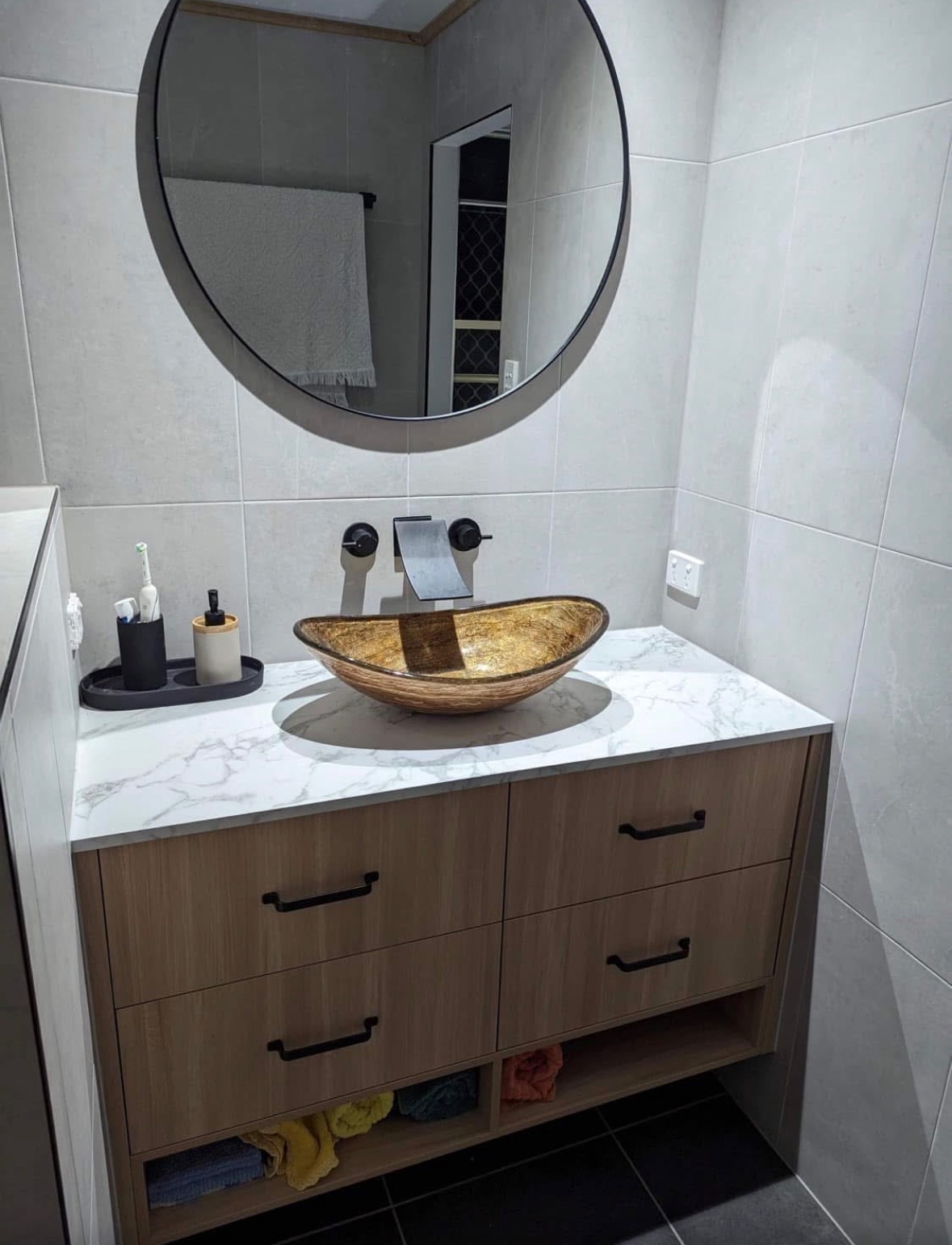 Custom bathroom vanity with marble top, gold vessel basin and round mirror — PMG Cabinetry